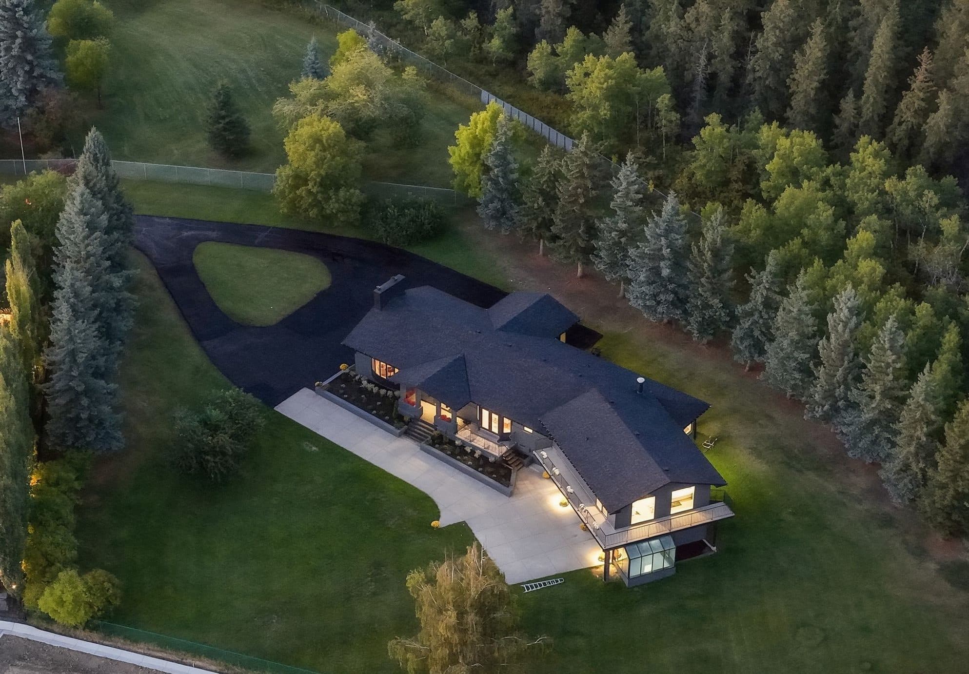 1008 Shawnee Drive SW at dusk, a private estate home among mature evergreens on a 1.07-acre lot in Shawnee Slopes, SW Calgary